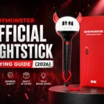 Promotional blog cover image for the BABYMONSTER Official Lightstick Buying Guide 2026 featuring the BABYMONSTER lightstick and red packaging box on a dark concert-style background with red lighting effects. Large bold text reads ‘BABYMONSTER Official Lightstick Buying Guide (2026)’ alongside icons highlighting authenticity, quality, box contents, and buying tips.